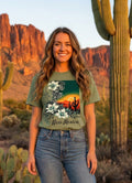 Woman standing in a desert landscape with cacti, wearing a New Mexico-themed t-shirt and jeans.